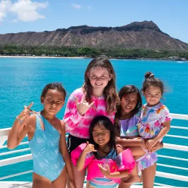 a group of people sitting on a bench next to a body of water