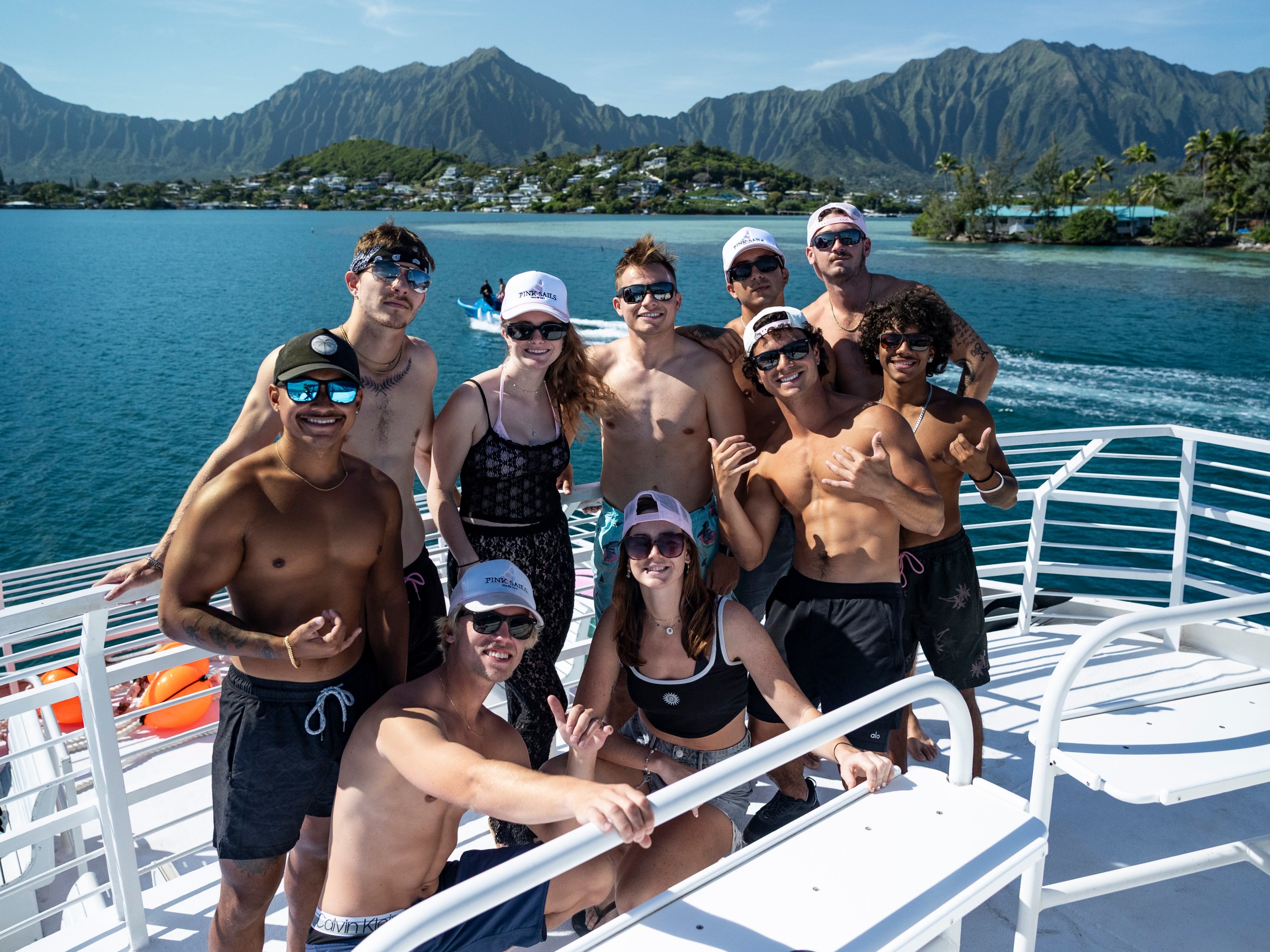 Group of people on a boat with mountains and ocean in the background.