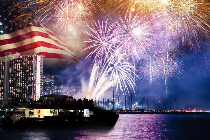 Fireworks over a city skyline with a boat on water and U.S. flag overlay.
