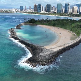 Aerial view of a coastal city with a sandy beach and rocky shoreline.