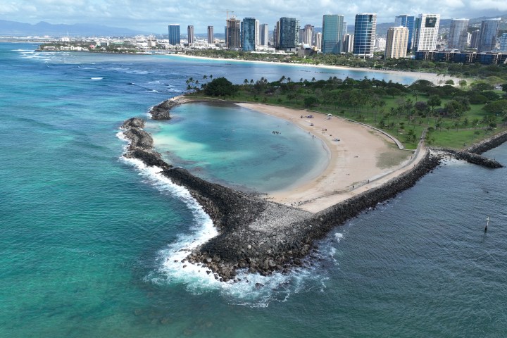 Aerial view of a coastal city with a sandy beach and rocky shoreline.